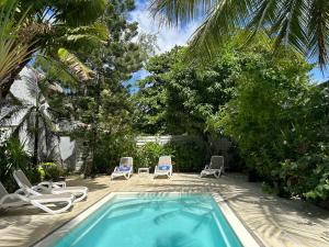 a swimming pool with lounge chairs and a palm tree at Lush Garden Villa with private pool in Trou aux Biches