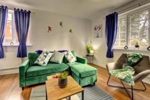 Spacious, Luxurious Cliffes في ليستر: غرفة معيشة مع أريكة خضراء وكرسيين