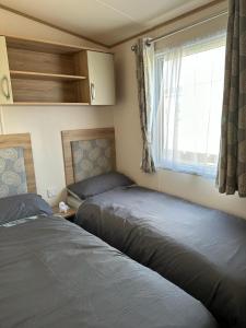 2 łóżka w małym pokoju z oknem w obiekcie Beautiful 3 bed Caravan in Felixstowe w mieście Felixstowe