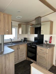 a kitchen with wooden cabinets and a black stove top oven at Beautiful 3 bed Caravan in Felixstowe in Felixstowe