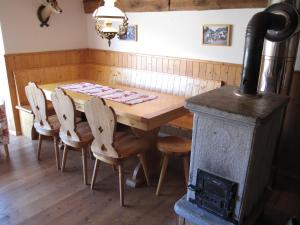 mesa de madera con sillas y estufa de leña en Mayen de Planraveire, en Orsières
