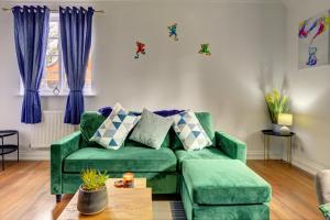 a living room with a green couch and blue curtains at Spacious, Luxurious Cliffes in Leicester