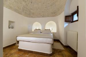a bedroom with a white bed with two arched windows at Villa Enò by Perle di Puglia in Noci