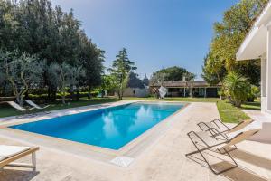 a swimming pool in a yard with chairs and a house at Villa Enò by Perle di Puglia in Noci