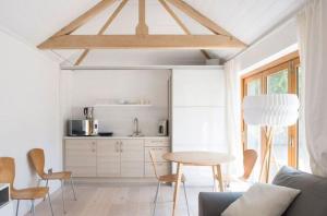 a living room with a table and a kitchen at Little Barn at Coppice Barn, Birdham in Birdham