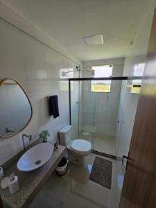 a bathroom with a toilet and a sink and a mirror at Ap barra grande com piscina in Marau