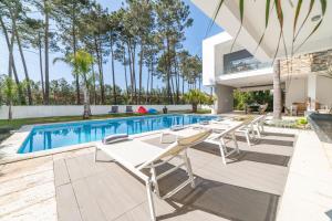 uma piscina com cadeiras e uma casa em Villa Mirage em Aroeira