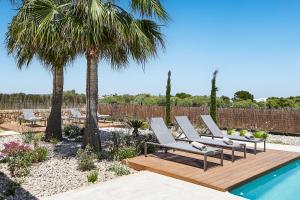 - un ensemble de chaises longues installées à côté de la piscine dans l'établissement Villa Es Trenc, à Campos