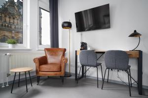 a room with three chairs and a desk with a television at Stylisches Studio im Herzen Leipzigs in Leipzig