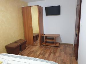 1 dormitorio con 1 cama, armario y TV en Pensiunea Vlahopol, en Pojorîta