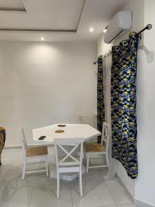 una sala da pranzo bianca con tavolo e sedie bianchi di RESIDENCE KWABO a Cotonou