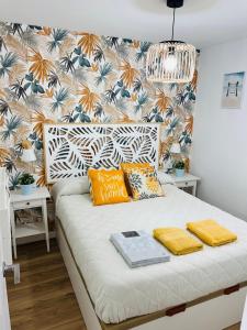 1 dormitorio con cama blanca y almohadas amarillas en APARTAMENTO NUEVO CÉNTRICO en PRIMERA Línea de playa con vistas al Mar, Piscina, aire acondicionado y wifi, en Peñíscola