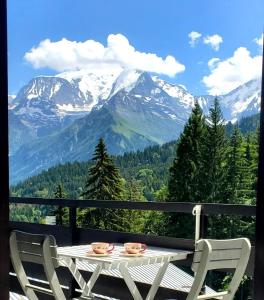 d'une table et de chaises sur un balcon avec vue sur la montagne. dans l'établissement Appartement Saint Gervais les Bains piscine et vue imprenable Mont Blanc, à Saint-Gervais-les-Bains