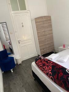 ein Schlafzimmer mit einem Bett, einem blauen Stuhl und einer Tür in der Unterkunft Tunis Lafayette in Tunis