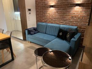 ein blaues Sofa in einem Zimmer mit Ziegelwand in der Unterkunft Apartament Faltom Marina Gdynia in Gdynia
