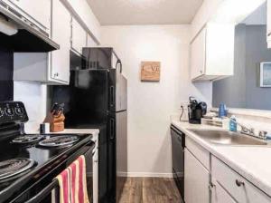 ダラスにあるAffordable Apartment with Balconyの黒い冷蔵庫とシンクのあるキッチン