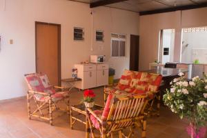 a living room with chairs and a table and a kitchen at Pousada Oliveira Guarda do Embaú in Guarda do Embaú