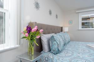 a vase of flowers on a table next to a bed at 100 NEW STUNNING HUGE HOME, GARDEN BEACH, RESERVED PARKING in Laguna Beach