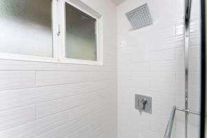 La salle de bains blanche est pourvue d'une douche et d'une fenêtre. dans l'établissement 100 NEW STUNNING HUGE HOME, GARDEN BEACH, RESERVED PARKING, à Laguna Beach