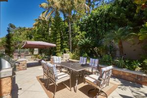 a table with chairs and an umbrella on a patio at UNEQUALLED LUXURY VILLA BEACH 7000ft 180 VIEW in Laguna Beach