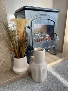 two white vases sitting on a shelf with a fireplace at Stones Throw Lodge in Padstow