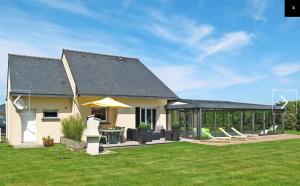 a house with a patio with chairs and an umbrella at Brittany, House with swimming pool and spa in the countryside in Kersaint-Plabennec
