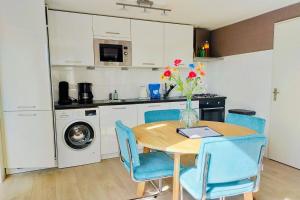 uma cozinha com uma mesa com cadeiras azuis e uma mesa com flores em Kustverhuur, Park Schoneveld, Duinroos 102 em Breskens