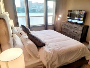 a bedroom with a white bed with pillows and a television at Lakeside Living w Trails, Music, Local Boutiques in Irving