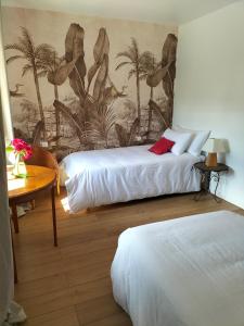 two beds in a hotel room with a mural of palm trees at La Mouillère in Verton
