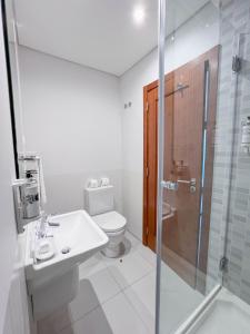 y baño con aseo, lavabo y ducha. en Villa Doris Suites, en Lagos