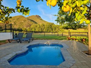 une terrasse avec une piscine, des chaises et une montagne dans l'établissement Klawerjas Flute Cottage, à Robertson
