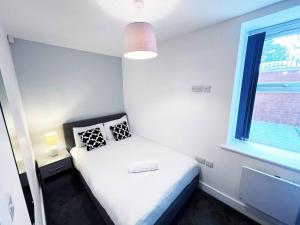 ein kleines Schlafzimmer mit einem Bett und einem Fenster in der Unterkunft FREE PARKING - Stunning 2-BR near Salford Royal in Manchester