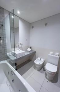 a white bathroom with a toilet and a sink at Villa Doris Suites in Lagos