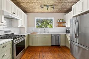 uma cozinha com armários brancos e um frigorífico de aço inoxidável em Welcome to Golden Field Farmhouse em Wellington