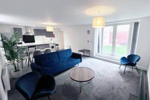 a living room with a blue couch and a kitchen at FREE PARKING - Stunning 2-BR near Salford Royal in Manchester