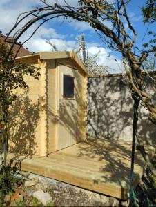 ein kleines Holzhaus mit einer Holzveranda in der Unterkunft Le Rosiers in Poissy