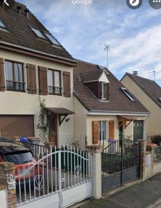 uma casa com uma cerca e um carro estacionado em frente em Le Rosiers em Poissy