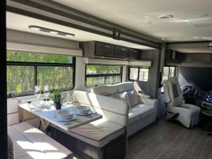 an rv living room with a table and a couch at The Magic Motor Home in Parkland