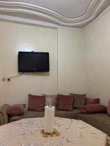 ein Wohnzimmer mit einem Sofa und einem TV an der Wand in der Unterkunft Appartement meublé à louer in Meknès