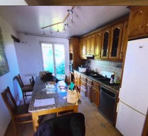 uma cozinha com uma mesa e um frigorífico em Le Rosiers em Poissy