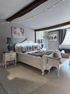 a white bedroom with a large bed and a chair at Church Farmhouse, Surrey, Sleeps 10, Large Garden in Crowhurst