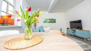 a vase of tulips on a table in a living room at Voll ausgestattetes, neues Rennsteig Apartment Ruhla in Ruhla
