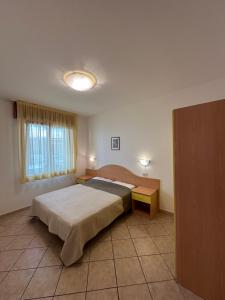 a bedroom with a bed and two tables and a window at Residence Guardamar - Agenzia Cocal in Caorle