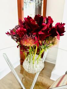 a vase filled with red flowers on a table at Charming Apartment in the Heart of Bath in Bath
