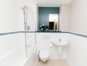 a white bathroom with a toilet and a sink at Marlin Apartments Commercial Road - Limehouse in London