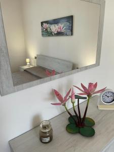 a vase with pink flowers on a table in front of a mirror at Water Lily Apartment in Bardello
