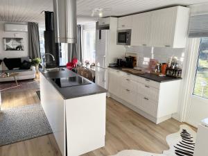 a kitchen with white cabinets and a black counter top at Nice cottage located by the lake Nommen in Björköby