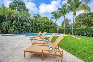 a row of lounge chairs next to a swimming pool at Samadhi - NEW 15 min drive to Ultra, by Newman Hospitality in Miami Shores