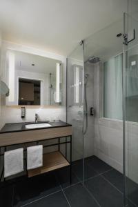 a bathroom with a sink and a glass shower at IntercityHotel Lübeck in Lübeck