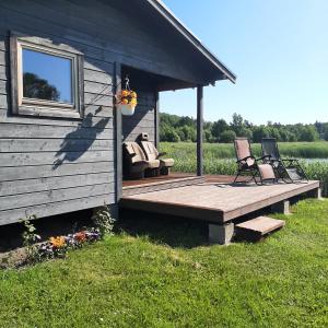 een hut met 2 stoelen en een houten terras bij Purvēveri in Tukums